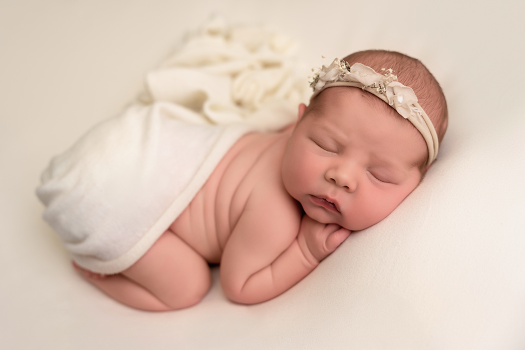 newborn girl on cream background with cream headband in bum up pose