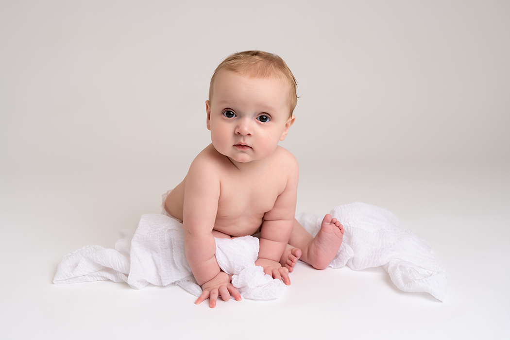 6 month old baby boy on simple white backdrop 